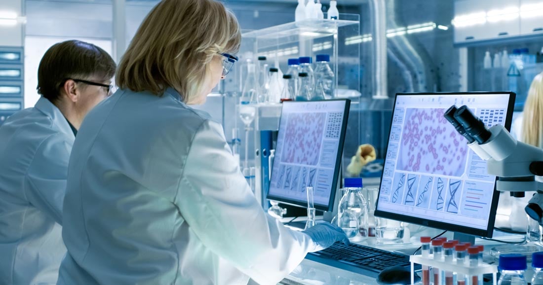 Two scientists at a lab bench with ELN on computer screen