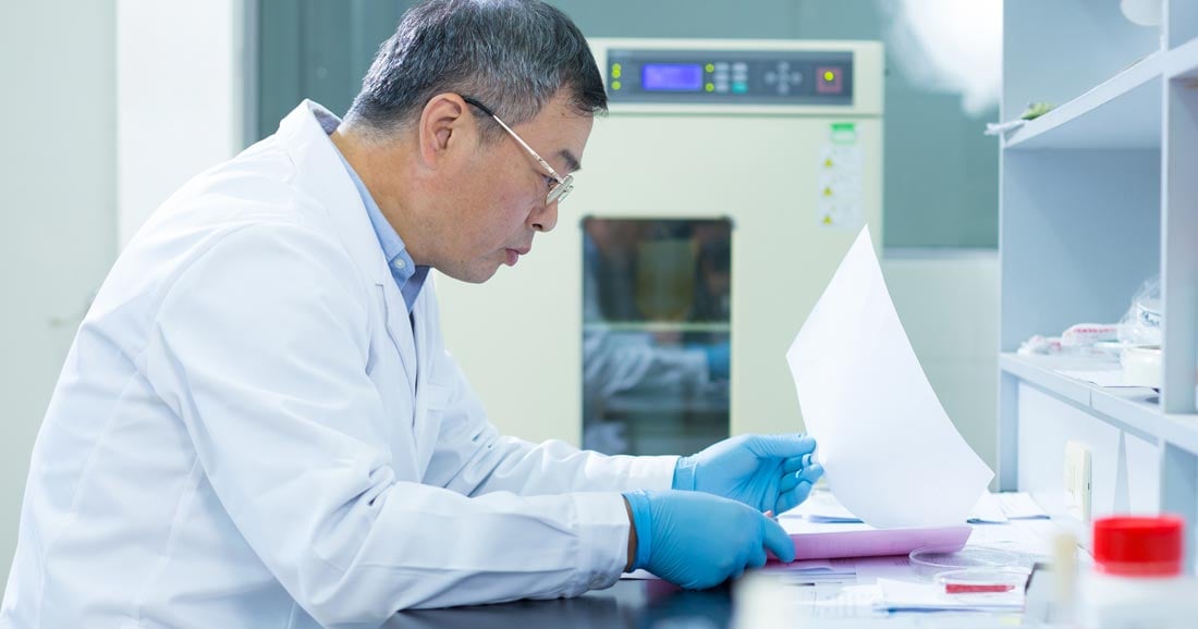 Image of scientist at bench reading paper-based notes